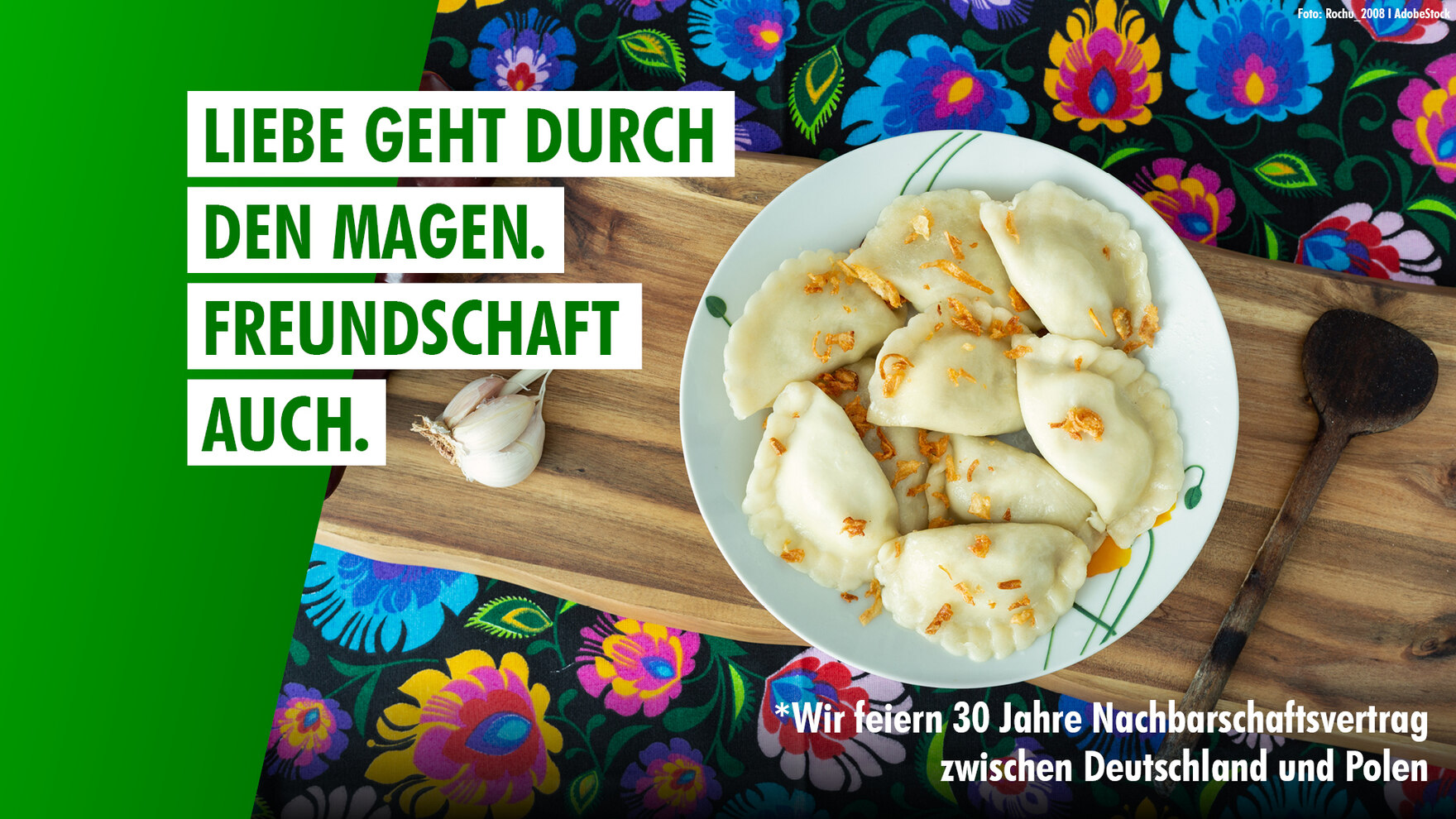 Schriftzug Liebe geht durch den Magen. Freundschaft auch. über einem Teller Pierogi