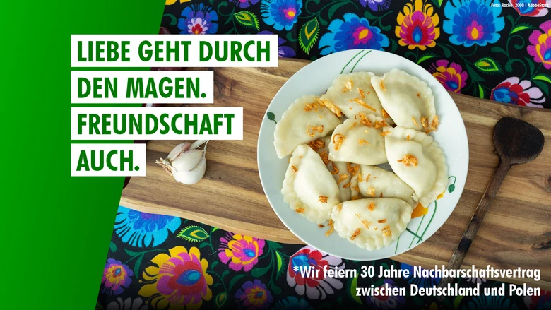 Schriftzug Liebe geht durch den Magen. Freundschaft auch. über einem Teller Pierogi